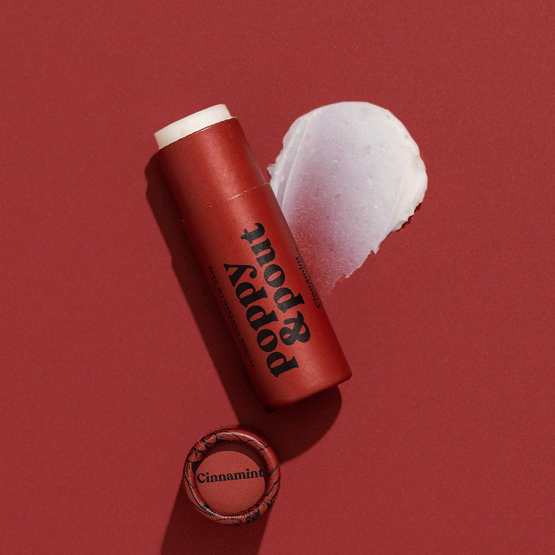 Red lip balm stick with white cream on a red background